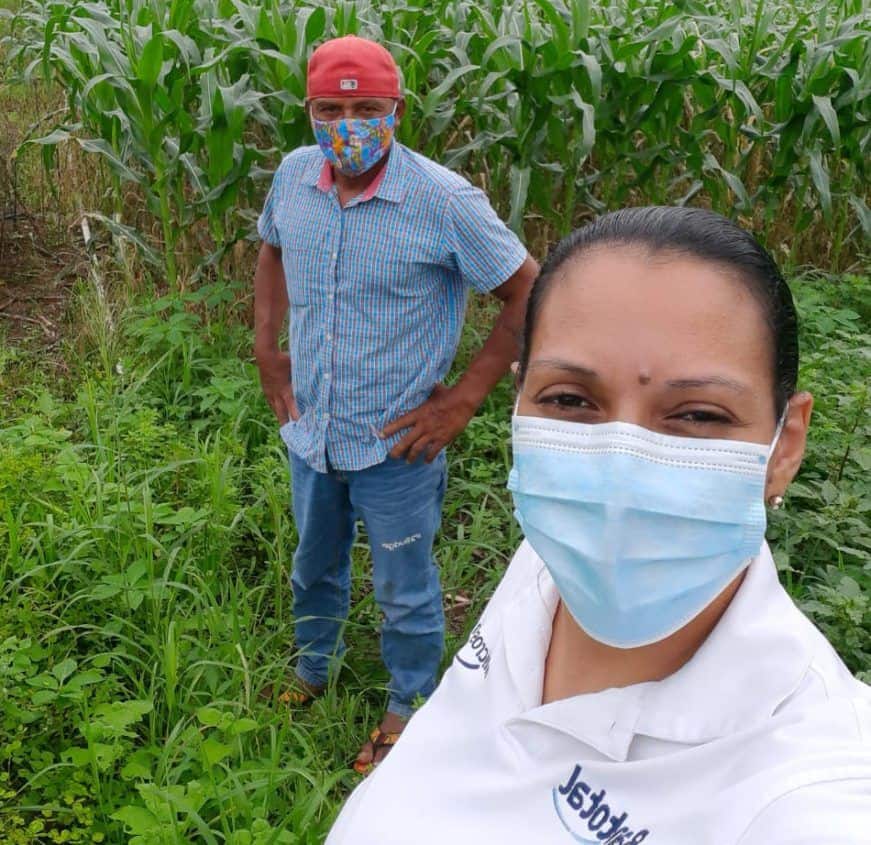 two people in a cornfield wearing masks